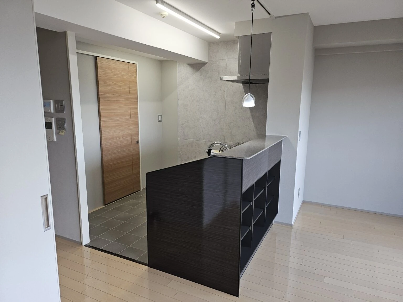 黒い腰壁の対面キッチンのあるマンションの室内